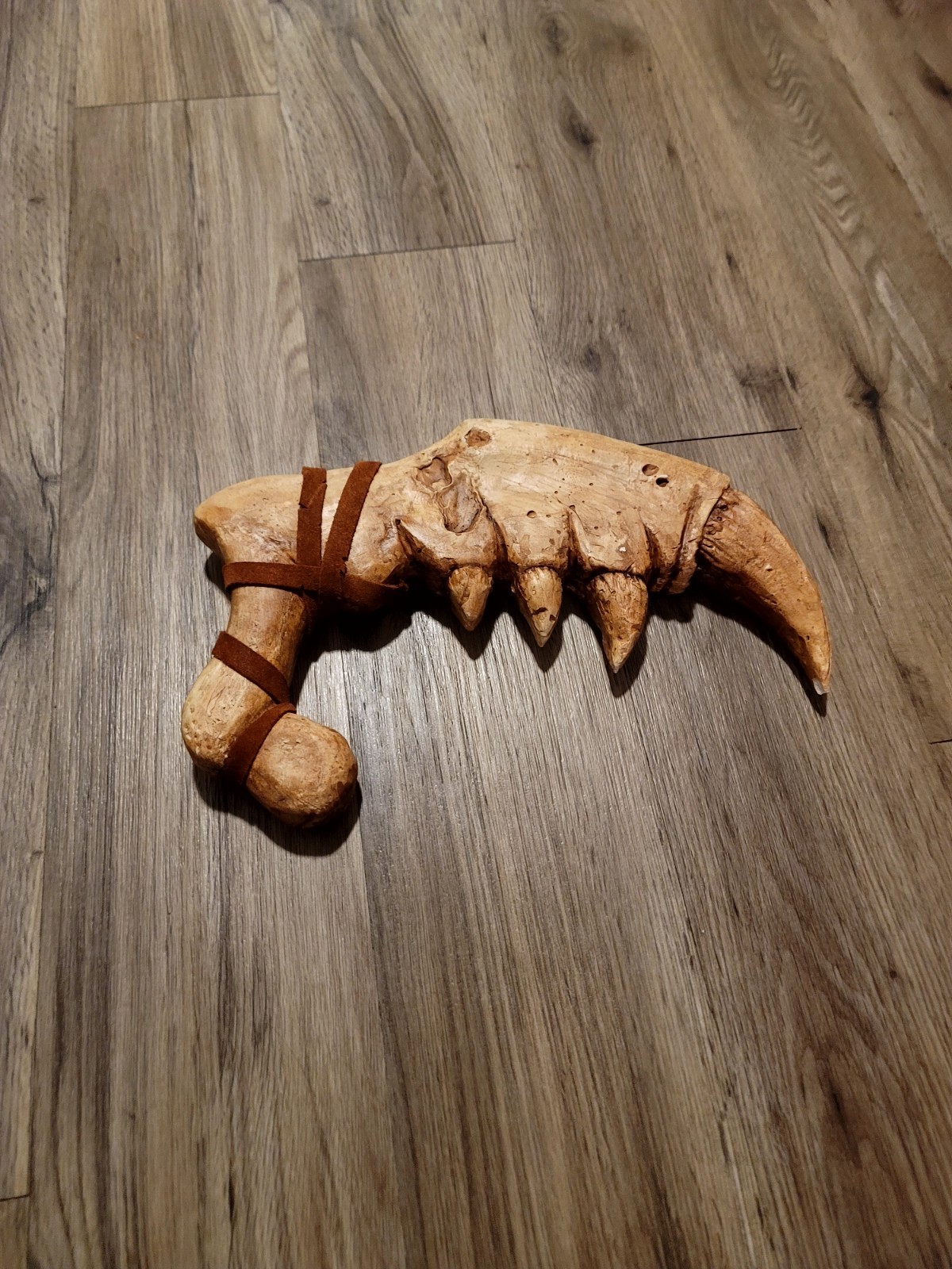 This is a genuine hand carved wooden claw dagger with brown leather straps....