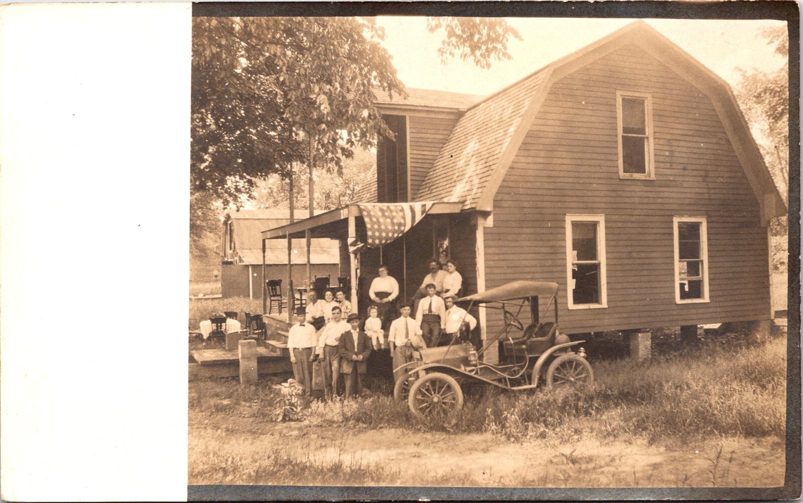 THIRTEEN PEOPLE ON FRONT PORCH OF HOUSE :AMERICAN FLAG :OLD CAR : RPPC 1904-1918 THIRTEEN PEOPLE ON FRONT PORCH OF HOUSE :AMERICAN FLAG :OLD CAR : RPPC 1904-1918